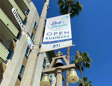 Shop Riverside Open Business Banner over University Ave. Street sign and the Raincross 
